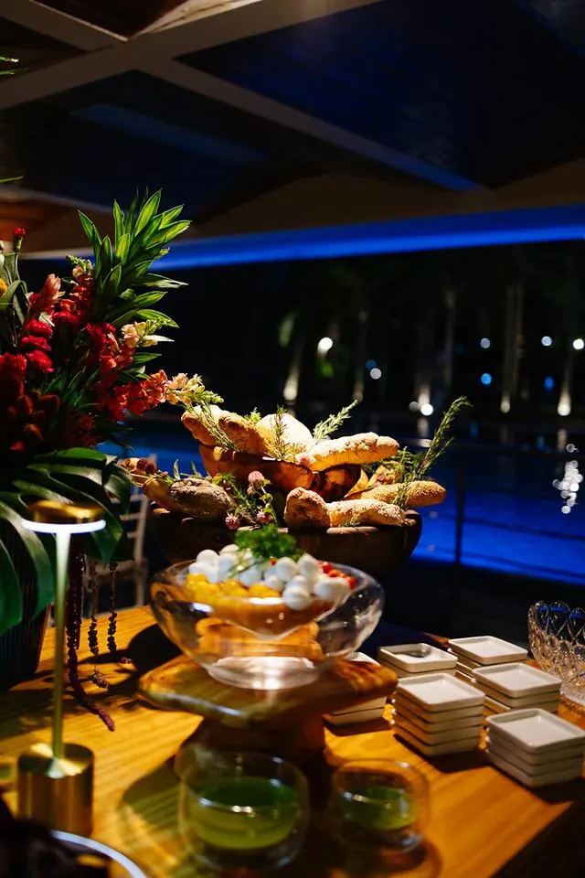 Mesa de buffet com pães artesanais e flores tropicais à noite